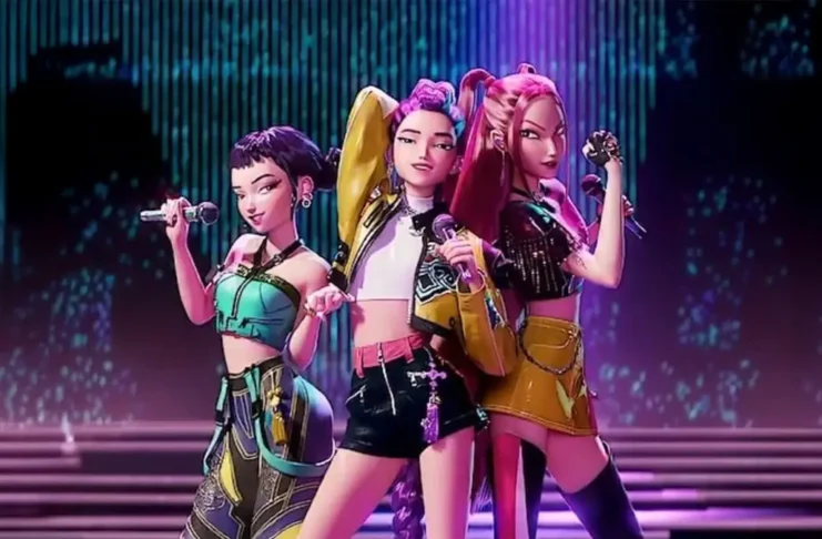 Tres integrantes animadas del grupo de K-pop Huntr/x cantando en un escenario con luces púrpuras y azules.